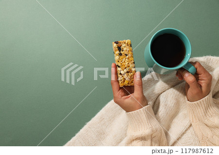 Granola bar with cup of tea in female hands 117987612