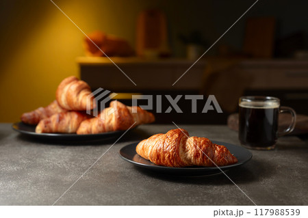 Fresh baked croissants and black coffee on a kitchen table. Fresh baked croissants and black coffee on a kitchen table. 117988539