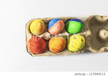 Colorful easter eggs in a cardboard box on a white background. Colorful easter eggs in a cardboard box on a white background. 117989113