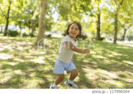 Carefree child running through sunny park on summer day 117990204