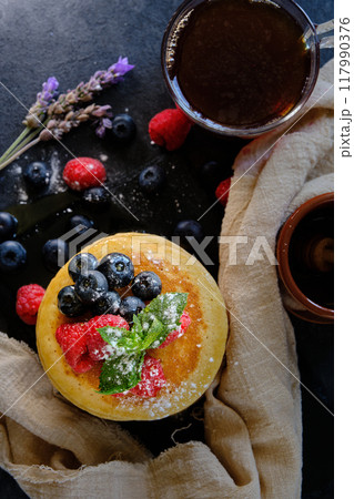 pancakes with berries and honey on dark background top view 117990376