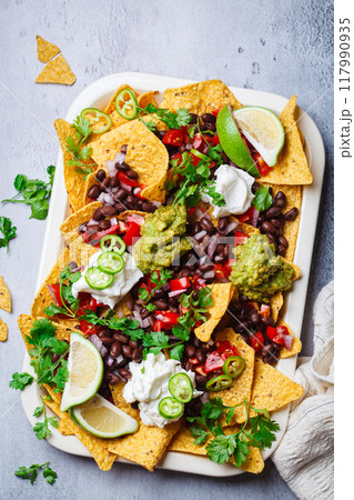 Vegan nachos with guacamole, black beans and salsa for a party. Vegan nachos with guacamole, black beans and salsa for a party. 117990935