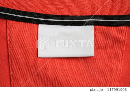 Blank white laundry care clothes label on orange shirt fabric texture background Blank white laundry care clothes label on orange shirt fabric texture background 117991908