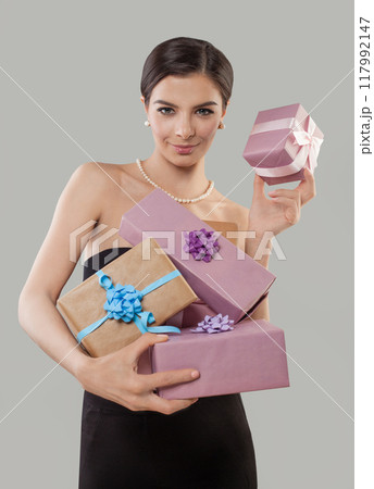 Elegant glamorous young woman holds beautiful gift box in hands and looks on the camera 117992147