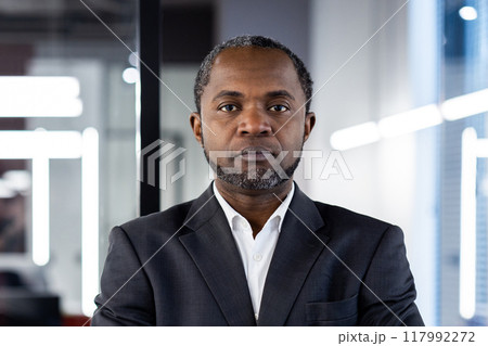 Portrait of confident businessman in formal suit standing in modern office, expressing leadership and professionalism. Ideal for corporate, business, and professional themes. 117992272