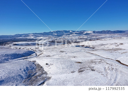 Aerial view of snow covered countryside hills with light snow Aerial view of snow covered countryside hills with light snow 117992535