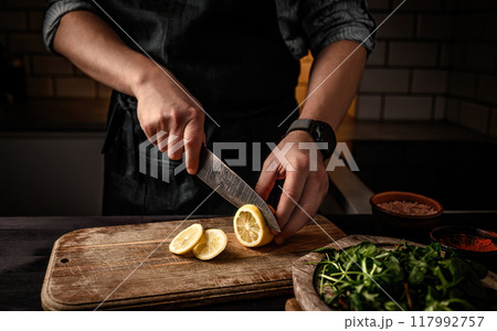 Chief hands cutting lemon to slices with knife 117992757