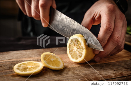 Chief hands cutting lemon to slices with knife 117992758