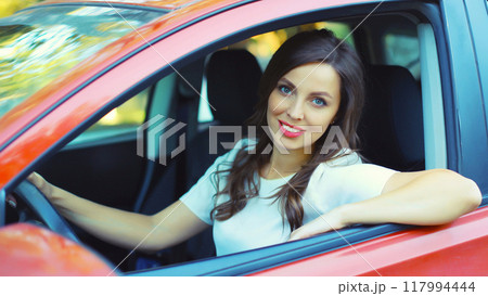 Happy smiling female driver sitting behind the wheel of car 117994444