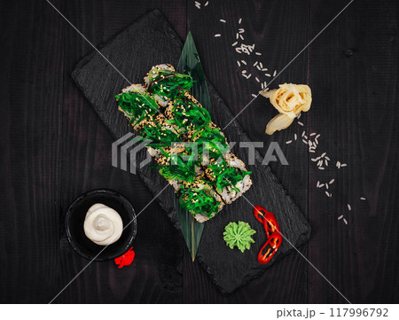 Delicious sushi rolls with algae and sesame seeds on black stone background Delicious sushi rolls with algae and sesame seeds on black stone background 117996792