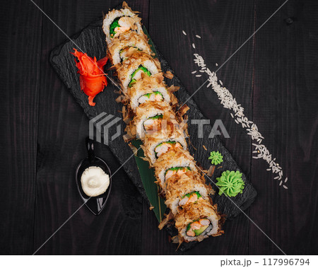 Tempura sushi roll being served on black slate platter 117996794
