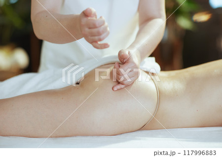 Massage therapist in spa salon massaging clients buttocks 117996883