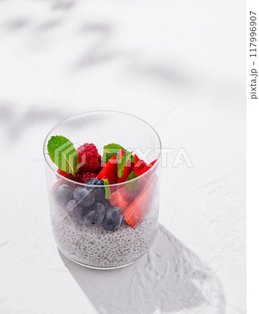 Chia seed pudding decorated with fresh berries and mint leaves on white background 117996907