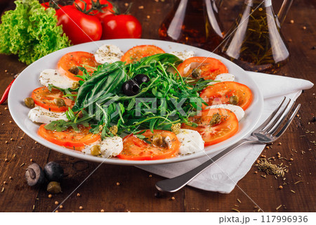 Caprese salad with tomatoes mozzarella and basil on wooden table 117996936
