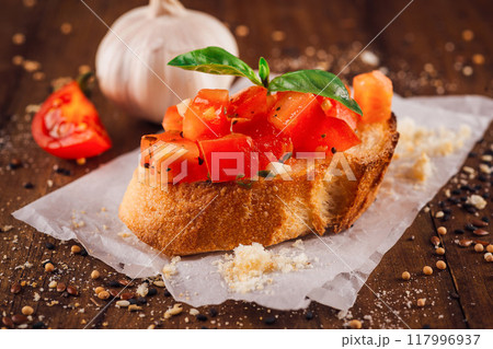 Delicious bruschetta with tomatoes and basil sitting on wooden table 117996937
