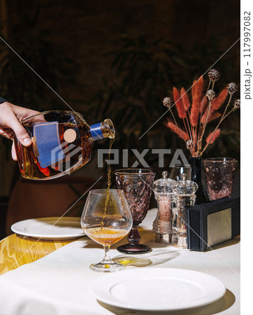 Waiter pouring cognac into glass on restaurant table 117997082