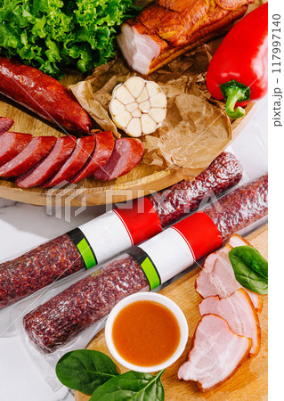 Variety of smoked and cured meat products is lying on the table 117997140