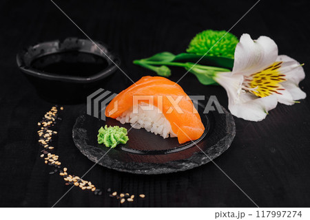 Fresh nigiri sushi with salmon on black slate with wasabi and soy sauce 117997274