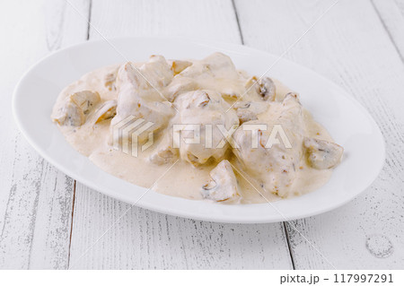 Chicken fricassee with mushrooms in creamy sauce on white plate 117997291