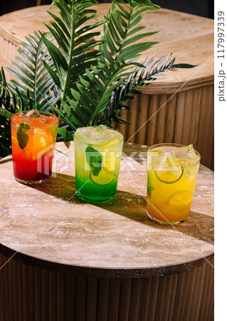 Three colorful refreshing summer cocktails standing on bar countertop 117997339