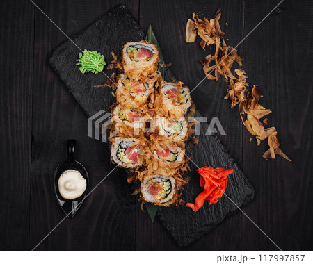 Sushi rolls set served on black stone plate on dark wooden table 117997857