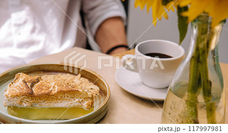 Lemon meringue pie and coffee being enjoyed by a customer in a cafe Lemon meringue pie and coffee being enjoyed by a customer in a cafe 117997981