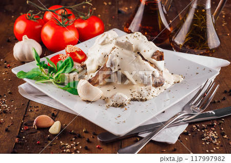 Grilled lamb ribs in creamy sauce served on white plate Grilled lamb ribs in creamy sauce served on white plate 117997982