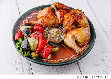 Roasted chicken with vegetables and sauce on rustic plate Roasted chicken with vegetables and sauce on rustic plate 117998017