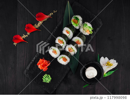 Fresh sushi rolls with salmon and avocado on black stone serving plate Fresh sushi rolls with salmon and avocado on black stone serving plate 117998098