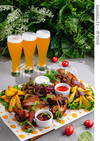Grilled meat and vegetables platter being served with three glasses of beer Grilled meat and vegetables platter being served with three glasses of beer 117998099