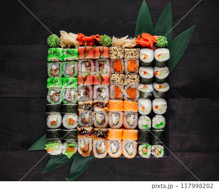 Large sushi set with variety of rolls being served on black wooden table background Large sushi set with variety of rolls being served on black wooden table background 117998202