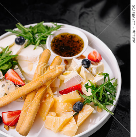 Gourmet cheese platter with fruits and breadsticks 117998750