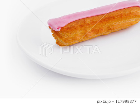 Pink frosted eclair on white plate 117998877