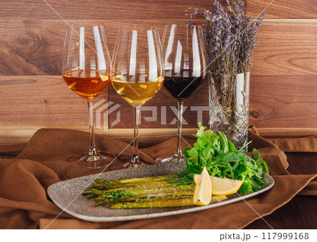 Grilled asparagus with lemon and arugula accompanied by three glasses of wine Grilled asparagus with lemon and arugula accompanied by three glasses of wine 117999168