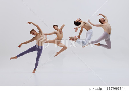 Dancers' synchronized leaps embody essence of creating art through intense physical training and dedication against white studio background. 117999544