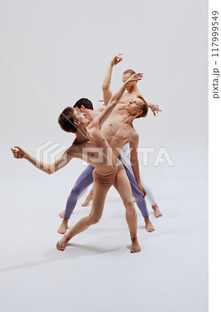 Group of dancers intertwines in motion, creating art with every step and stretch, showcasing their training against white studio background. 117999549