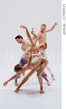 Dancers focus on their forms, exercising strength and flexibility to achieve their intricate choreography against white studio background. Dancers focus on their forms, exercising strength and flexibility to achieve their intricate choreography against white studio background. 117999551
