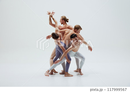 Group of dancers entwine their bodies in complex pose, capturing beauty of synchronized movement against white studio background. 117999567