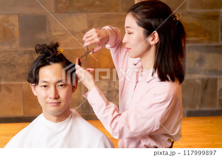 お客の髪を切る女性ヘアスタイリスト　ヘアサロン　美容室　イメージ 117999897