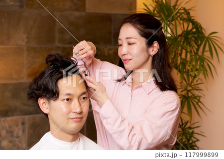 お客の髪を切る女性ヘアスタイリスト　ヘアサロン　美容室　イメージ 117999899