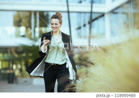 woman employee near business center using phone and walking 118000480