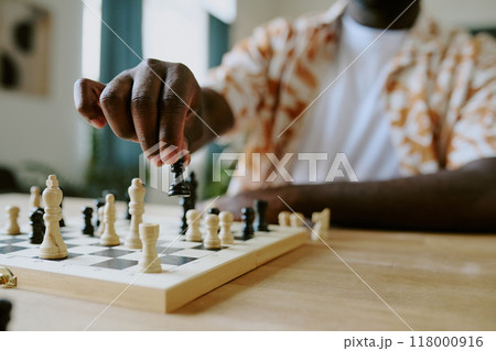 Closeup of hand of unrecognizable African American male chess player moving pawn piece, copy space Closeup of hand of unrecognizable African American male chess player moving pawn piece, copy space 118000916