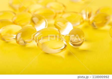 Omega 3 fish oil on yellow background. Vitamins in soft capsules, cod liver oil closeup. Concept of healthcare, supplements, vitamin D, treatment of diseases. Copy space, banner. High quality photo Omega 3 fish oil on yellow background. Vitamins in soft capsules, cod liver oil closeup. Concept of healthcare, supplements, vitamin D, treatment of diseases. Copy space, banner. High quality photo 118000992