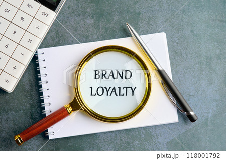 Conceptual brand loyalty symbol. Copy space. BRAND LOYALTY through a magnifying glass on a blank sheet of notepad on a gray background Conceptual brand loyalty symbol. Copy space. BRAND LOYALTY through a magnifying glass on a blank sheet of notepad on a gray background 118001792