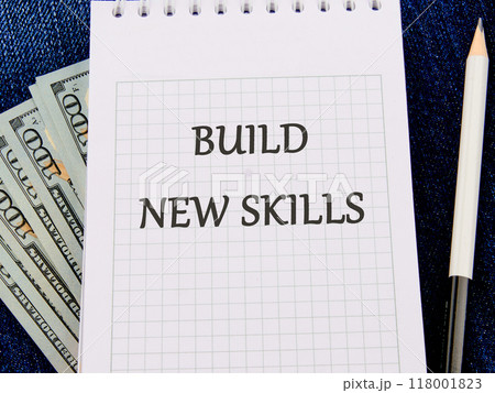 Business, education build new skills concept. Copy space. Concept word BUILD NEW SKILLS on a piece of paper on dollar bills Business, education build new skills concept. Copy space. Concept word BUILD NEW SKILLS on a piece of paper on dollar bills 118001823