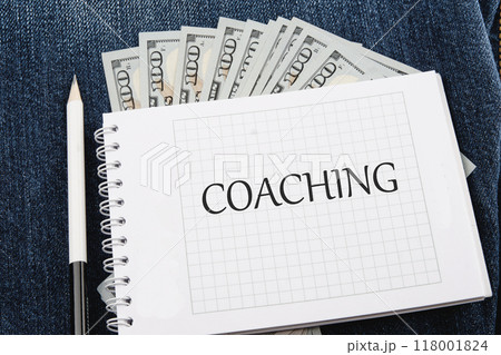 COACHING written on a checkered notebook against the background of American paper bills 118001824