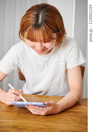 家でタブレットを操作する女性 118002284
