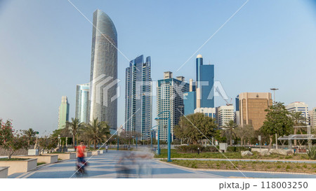 Corniche boulevard beach park along the coastline in Abu Dhabi timelapse with skyscrapers on background. 118003250