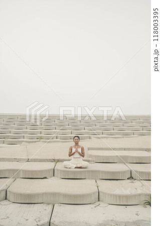 海辺に座ってヨガをしている若い女性 海辺に座ってヨガをしている若い女性 118003395