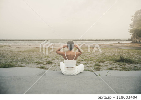 海辺に座ってヨガをしている若い女性 海辺に座ってヨガをしている若い女性 118003404